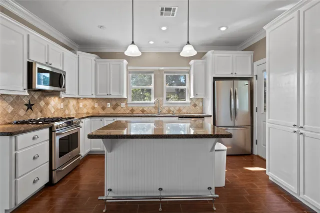 a kitchen with stainless steel appliances granite countertop a stove a sink and a refrigerator