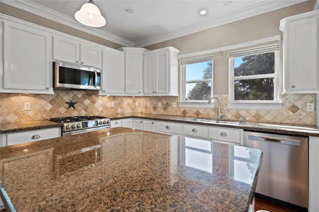 a kitchen with granite countertop a stove sink and microwave