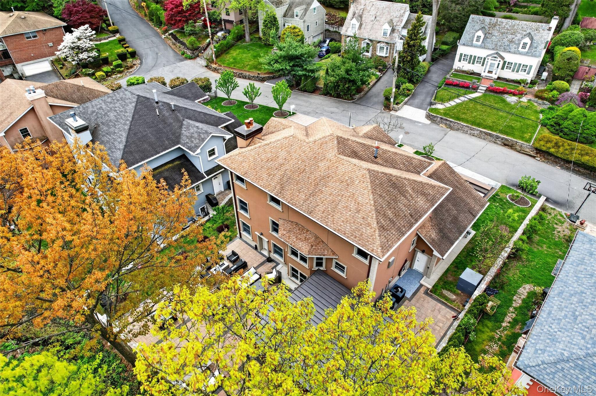65 Wildway Bronxville, NY 10708 - Photo 14 of 42 Aerial perspective showcasing a multi-level dwelling with a light brown shingle roof, tan stucco exterior, and multiple windows