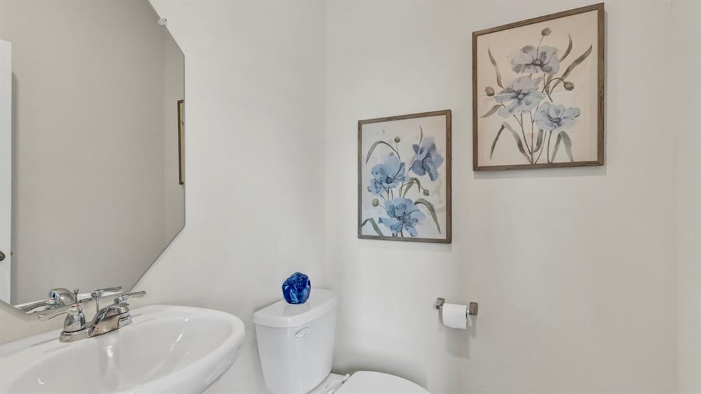 124 Pheasant Run Road Terrell, TX 75160 - Photo 3 of 35 Bathroom featuring a pedestal sink with chrome fixtures, a modern toilet, and a geometric mirror