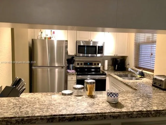 a kitchen with granite countertop a refrigerator and a stove top oven
