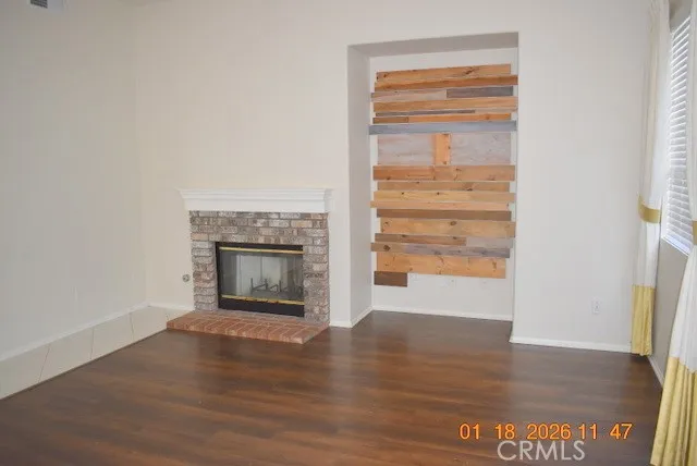 an empty room with wooden floor fireplace and windows