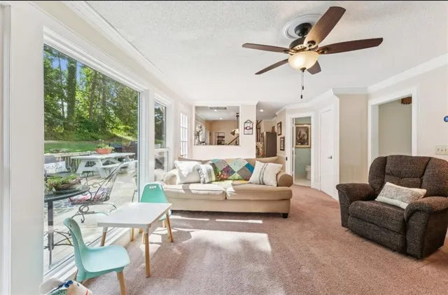 a living room with furniture ceiling fan and a large window