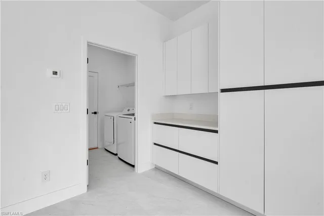 a white kitchen with cabinets and a table