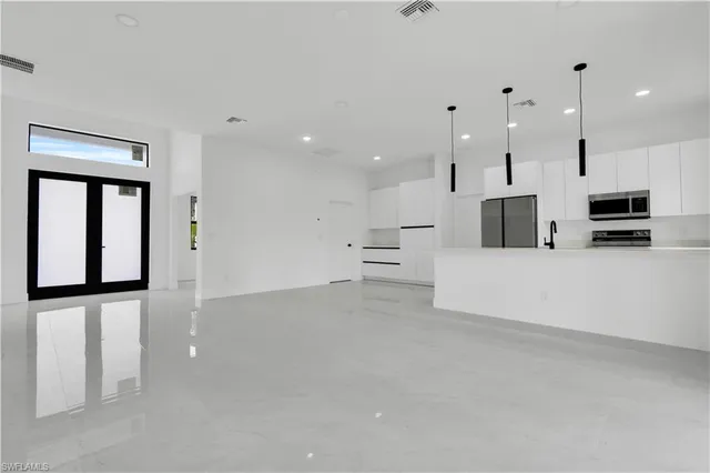 a large white kitchen with a large window and stainless steel appliances