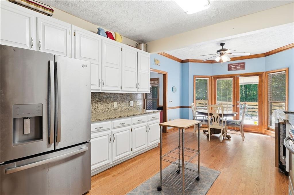 2737 John Petree Road Powder Springs, GA 30127 - Photo 13 of 55 a kitchen with stainless steel appliances granite countertop a refrigerator a stove and white cabinets with wooden floor