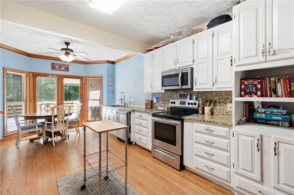 2737 John Petree Road Powder Springs, GA 30127 - Photo 14 of 55 a open kitchen with granite countertop a stove top oven a sink a dining table and chairs with wooden floor