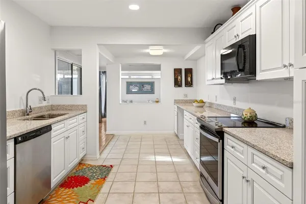 a kitchen with granite countertop white cabinets and white appliances