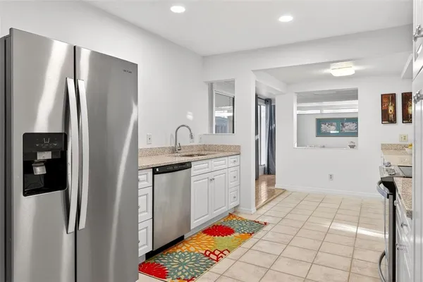 a large kitchen with granite countertop white cabinets and white appliances