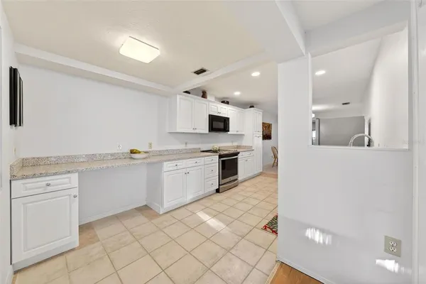 a view of hallway with granite countertop cabinets and a refrigerator