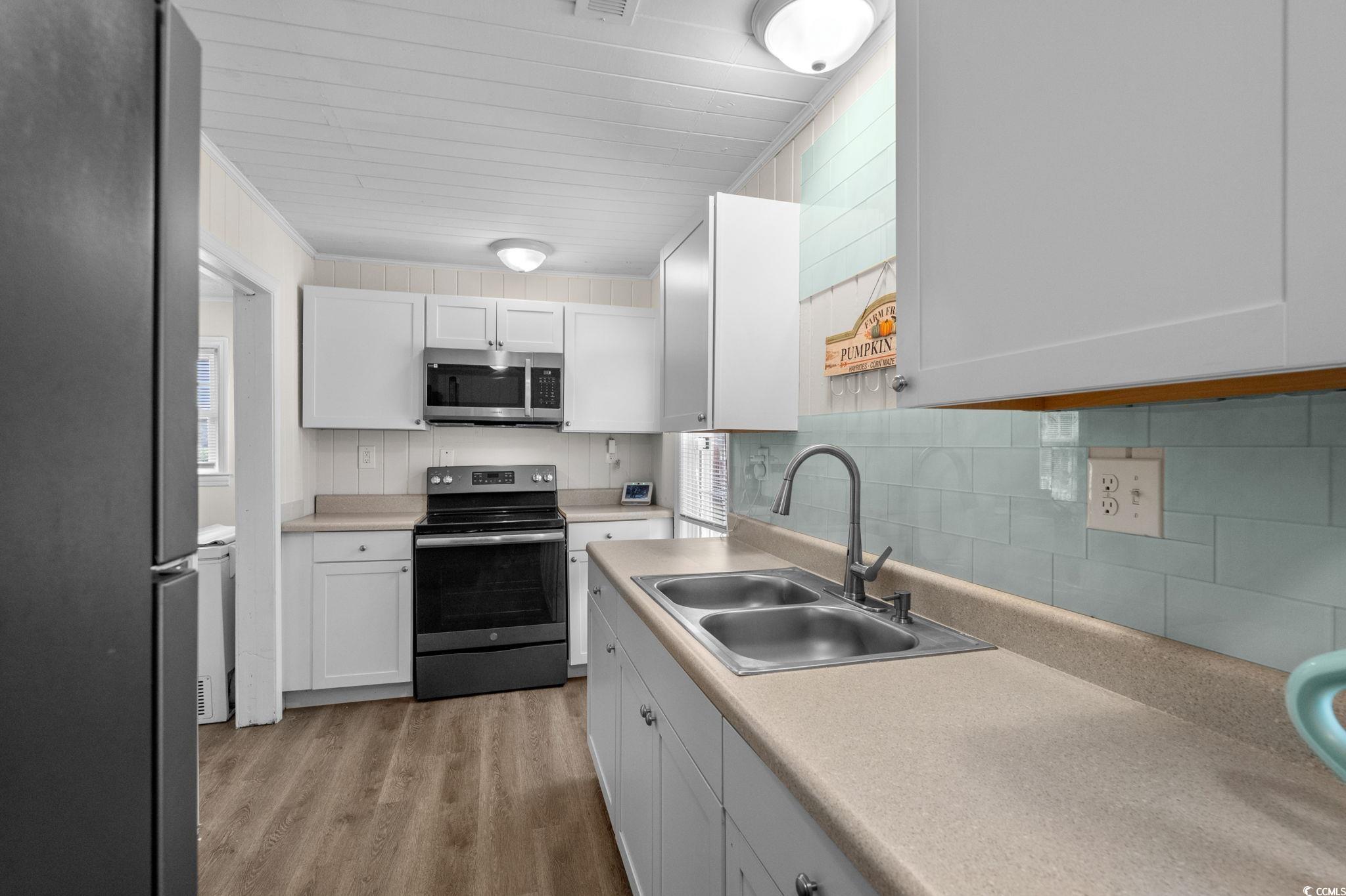 2475 Beverly Road Conway, SC 29527 - Photo 15 of 34 Kitchen featuring stainless steel appliances, light countertops, white cabinetry, light wood-style floors, and backsplash