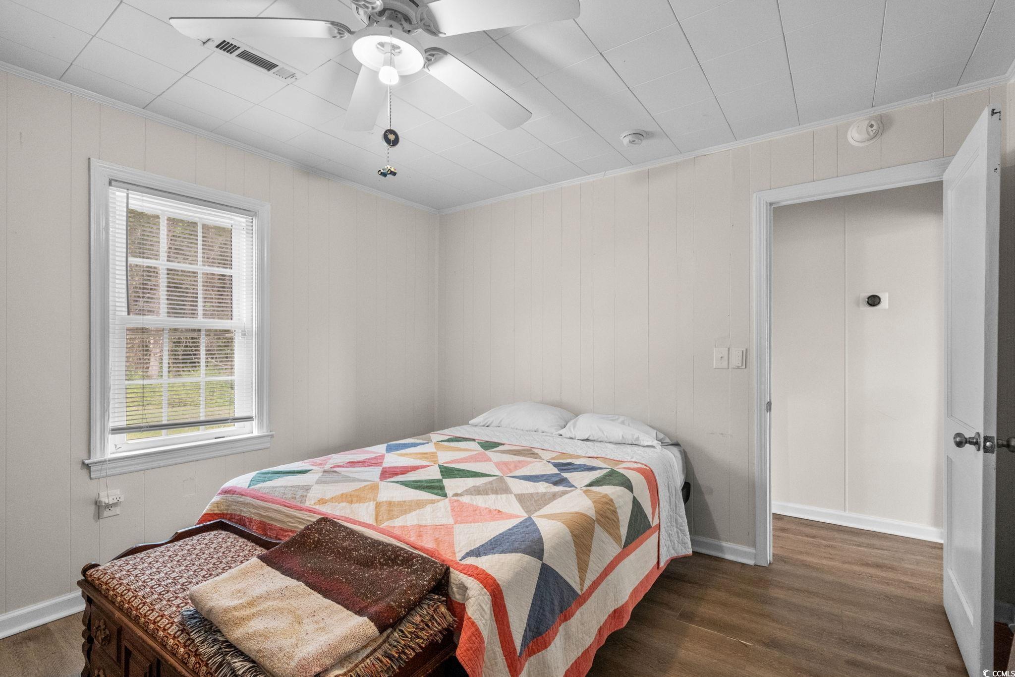 2475 Beverly Road Conway, SC 29527 - Photo 18 of 34 Bedroom with dark wood-type flooring, a ceiling fan, crown molding, and wooden walls
