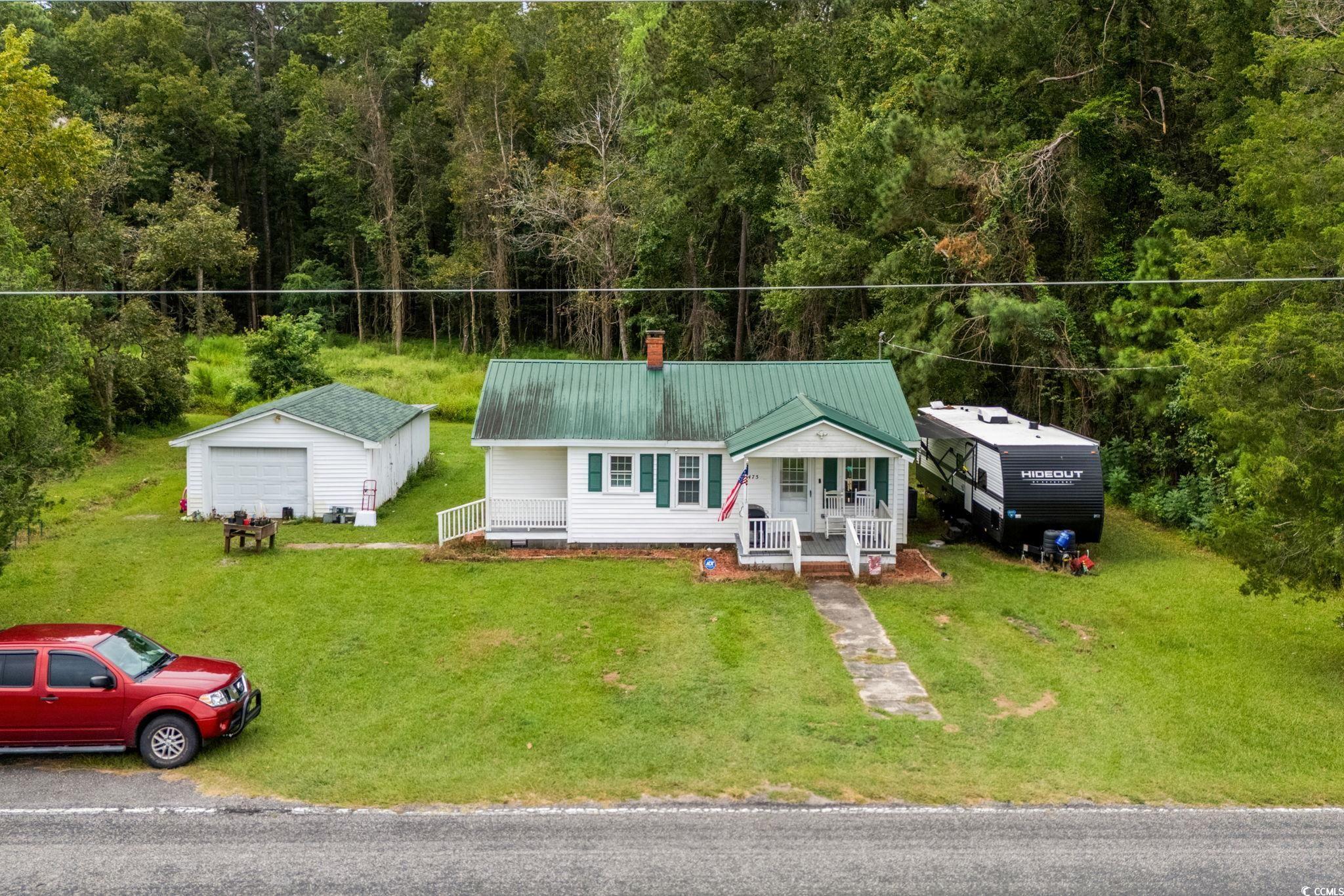 2475 Beverly Road Conway, SC 29527 - Photo 3 of 34 View of front facade featuring an outbuilding, a metal roof, a front yard, a wooded view, and a chimney