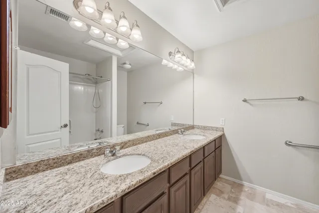 a bathroom with a granite countertop double vanity sink and a mirror