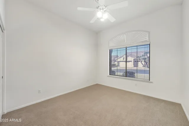 an empty room with a window and a fan