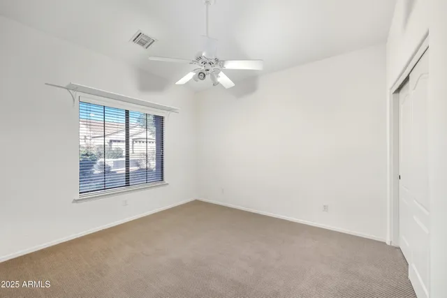an empty room with a window and ceiling fan