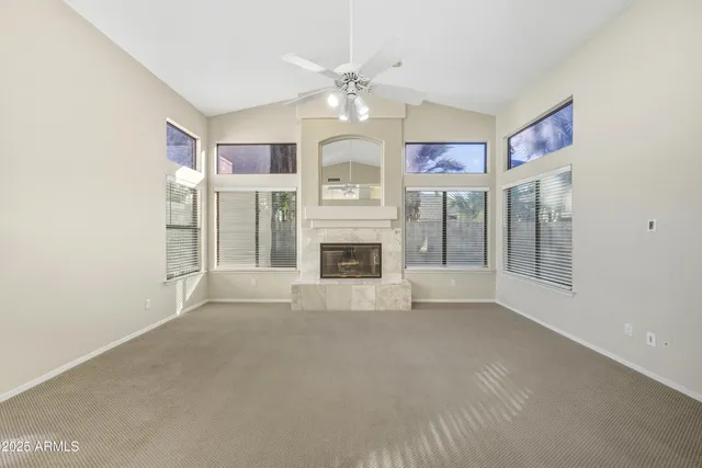 a view of an empty room with chandelier fan and fire place