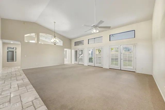 an empty room with windows and ceiling fan