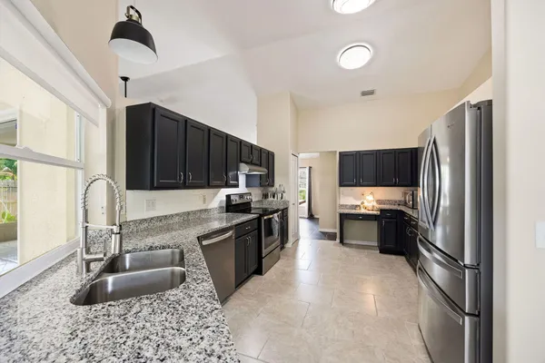 a kitchen with granite countertop stainless steel appliances a sink stove top oven and refrigerator