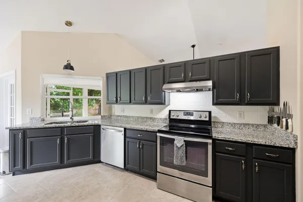 a kitchen with stainless steel appliances granite countertop a stove a sink and a microwave