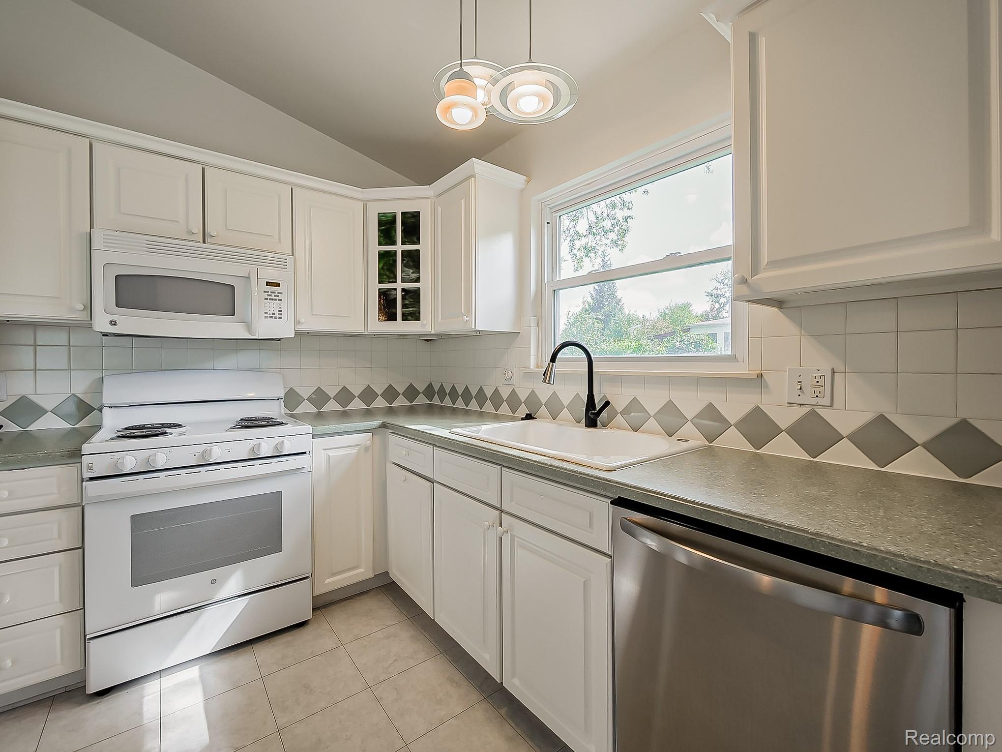 42195 Park Ridge Road Novi, MI 48375 - Photo 2 of 52 White cabinetry, stainless steel dishwasher, tile flooring, window over sink, and recessed lighting