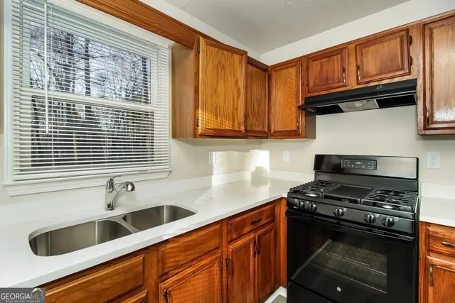 a kitchen with granite countertop a sink and a stove next to a window