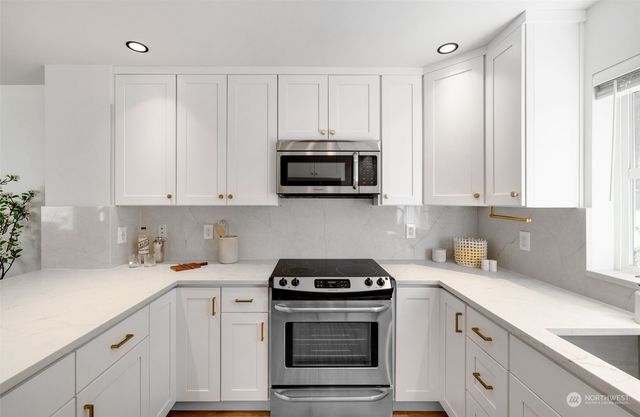 a kitchen with granite countertop white cabinets and stainless steel appliances