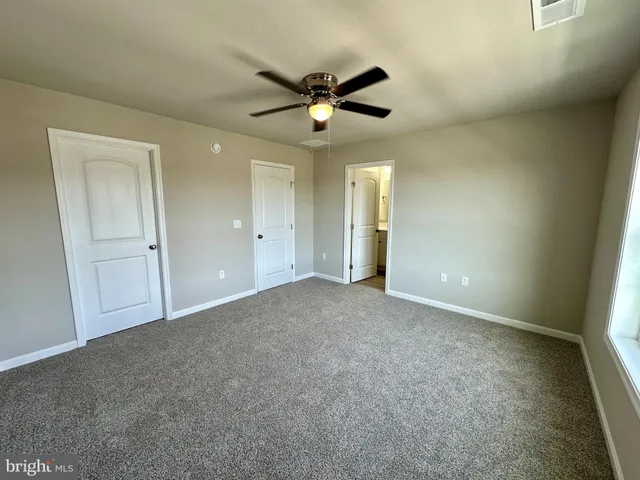 an empty room with closet and fan