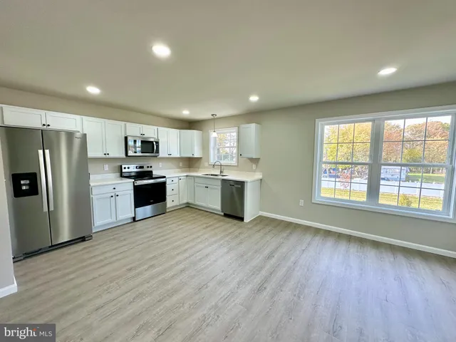 a kitchen with stainless steel appliances granite countertop a refrigerator a sink dishwasher a stove with wooden floors and cabinets