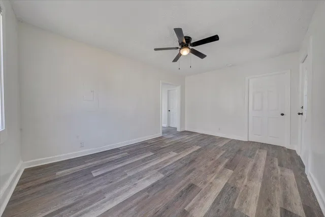 a view of empty room with wooden floor and ceiling fan