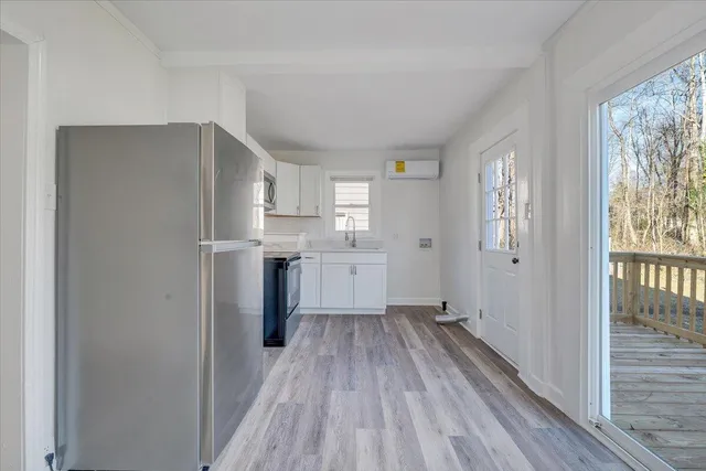 a kitchen with white cabinets and wooden floor