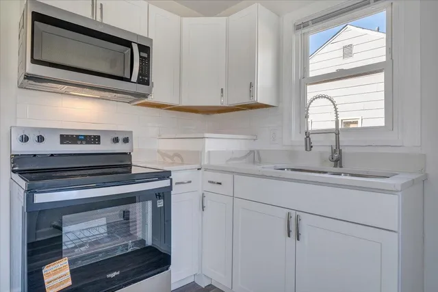 a kitchen with stainless steel appliances granite countertop white cabinets and a stove top oven