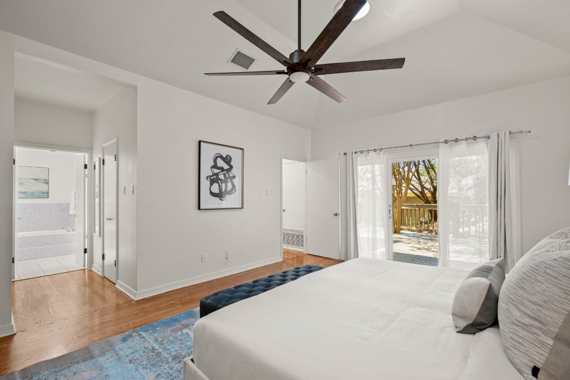 4906 Bob Cat Run Austin, TX 78731 - Photo 11 of 37 Bedroom with wood finished floors, access to outside, a ceiling fan, connected bathroom, and vaulted ceiling