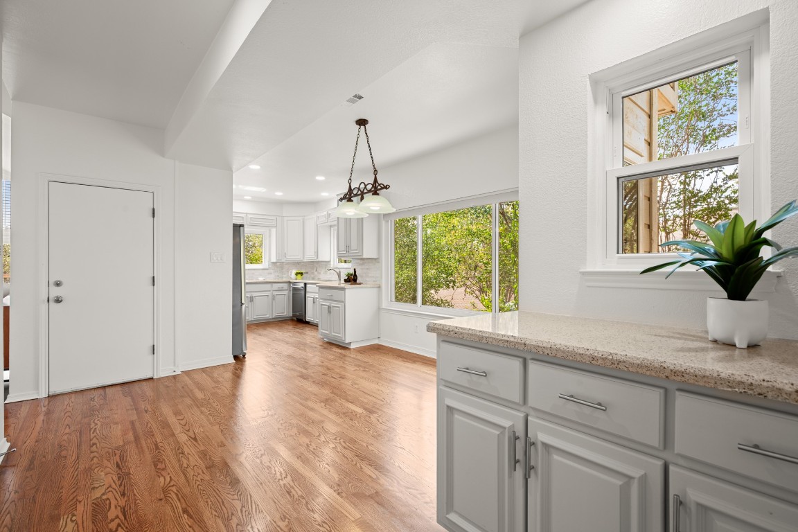 4906 Bob Cat Run Austin, TX 78731 - Photo 13 of 37 Kitchen with light wood-style floors, decorative light fixtures, decorative backsplash, light stone counters, and recessed lighting