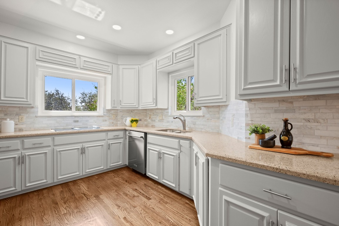 4906 Bob Cat Run Austin, TX 78731 - Photo 5 of 37 Kitchen featuring decorative backsplash, light stone countertops, light wood-type flooring, white cabinetry, and recessed lighting
