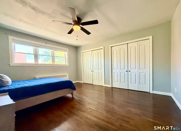 a view of empty room with wooden floor and fan