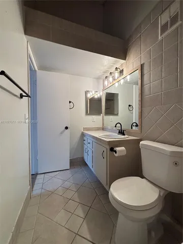 a bathroom with a granite countertop toilet a sink and mirror