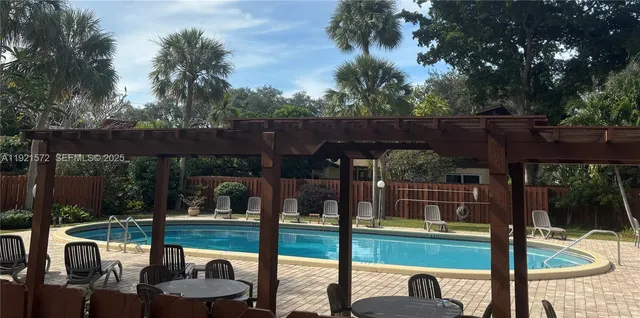 a view of roof deck with table and chairs potted plants with wooden floor and fence