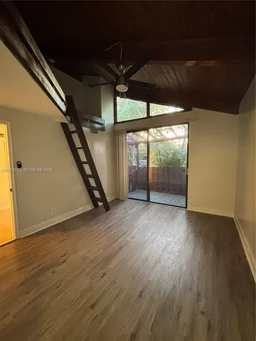 a view of an empty room with wooden floor and windows