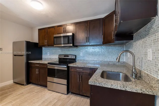 a kitchen with stainless steel appliances granite countertop a sink stove and refrigerator