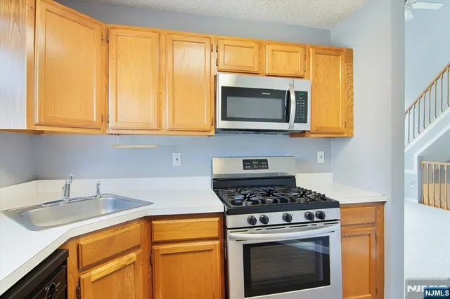 a kitchen with granite countertop cabinets stainless steel appliances a stove and a sink