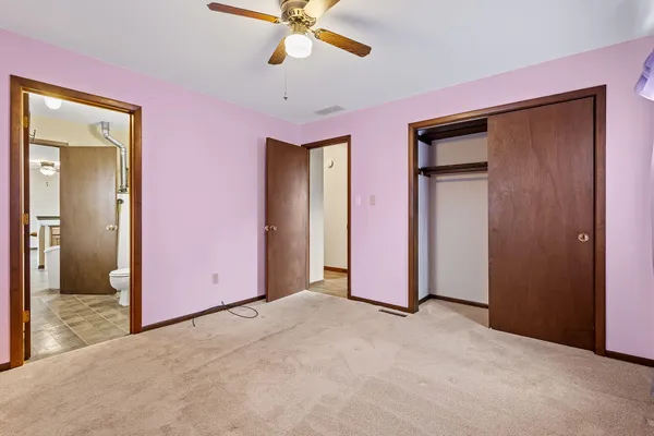 an empty room with closet and a chandelier fan