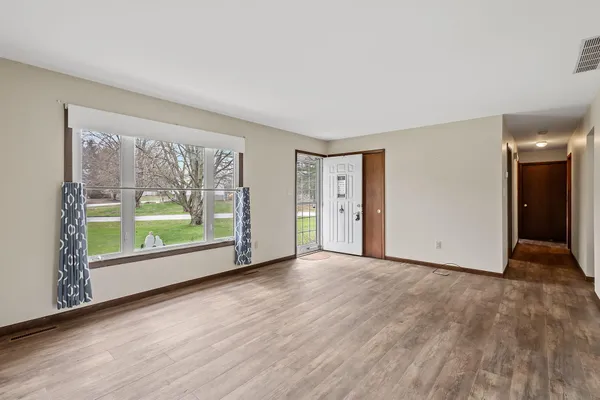 a view of an empty room with wooden floor and a window