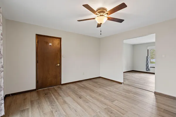 an empty room with wooden floor and a ceiling fan