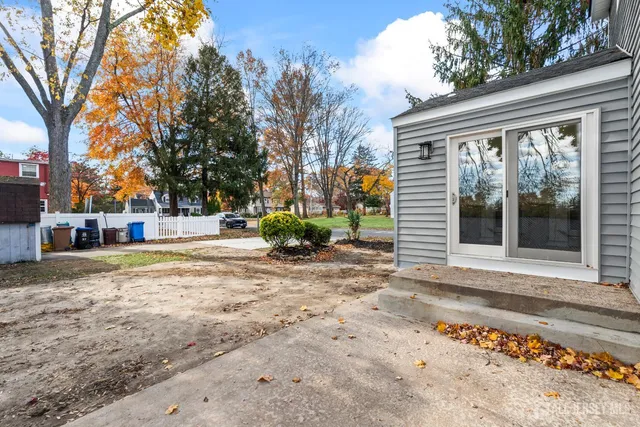 a backyard of a house with wooden fence and large trees