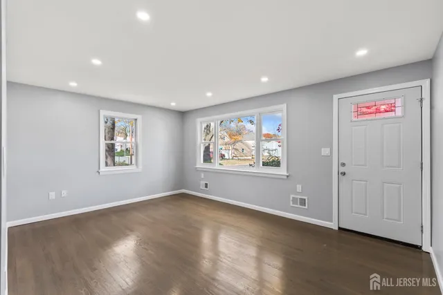 an empty room with wooden floor and window