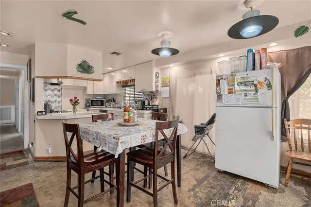 a kitchen with stainless steel appliances granite countertop a dining table chairs and a refrigerator
