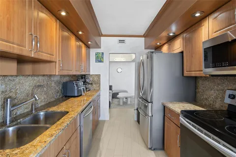 a kitchen with stainless steel appliances granite countertop a refrigerator a stove and a sink with wooden floor