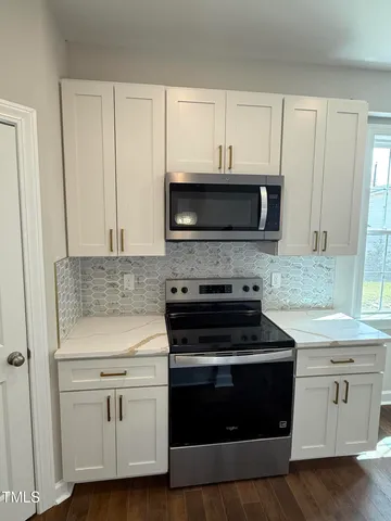 a kitchen with white cabinets and appliances
