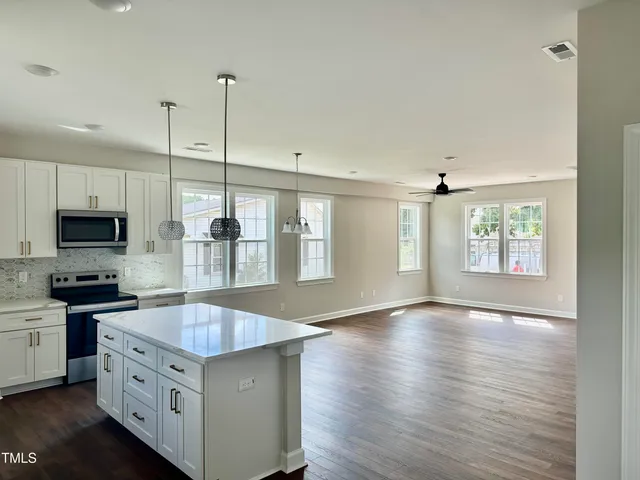 a kitchen with stainless steel appliances granite countertop a sink a stove and a wooden floors